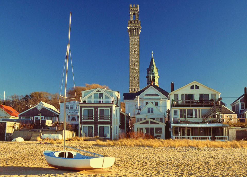 Looking inland from a sandy beach to a row of beachfront homes. A sailboat is sitting on the sand in the foreground.